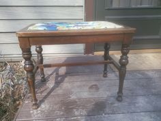 an old wooden table with a painting on it's top sitting in front of a house