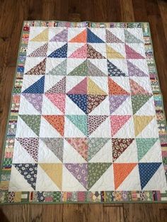 a multicolored quilt is laying on the floor next to a wooden table top