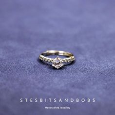 a gold ring with a diamond on it sitting on top of a purple cloth covered surface