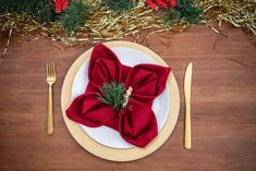 a place setting with red napkins and silverware on a wooden table surrounded by christmas decorations