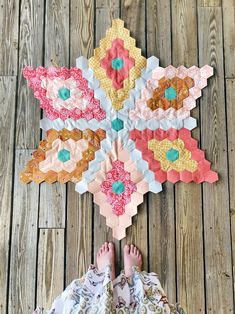 someone's feet on the floor next to a colorful piece of art made out of hexagon tiles