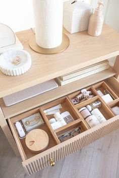 an open drawer on top of a wooden table next to a vase and other items