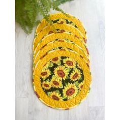 yellow sunflower coasters on white wood floor with green plant in the background, closeup