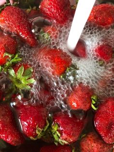 strawberries are being washed in a pot with water