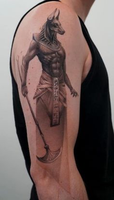 an egyptian tattoo on the back of a man's upper arm, showing his body and