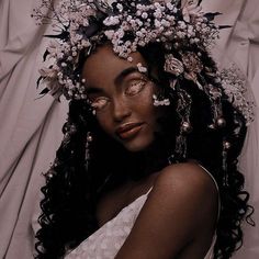 a woman with flowers in her hair is laying on the bed and looking at the camera