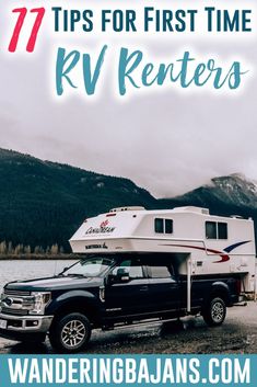 a truck with a camper on the back parked in front of water and mountains