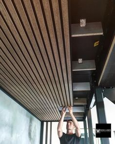 a man is fixing the ceiling in a room with wood slats and metal beams