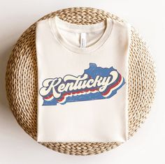 Show off your Kentucky pride with this unique retro design t-shirt! Featuring an eye-catching vintage-inspired design of the state of Kentucky, this t-shirt is perfect for anyone who loves their home state. Whether you're a native Kentuckian or just a fan of the state, this t-shirt is sure to show your bluegrass spirit. Made from a comfortable blend of cotton, this t-shirt is sure to become a wardrobe staple. Show off your Kentucky pride with this unique and stylish t-shirt! Or give as a gift!! shirt details: This classic unisex jersey short sleeve tee fits like a well-loved favorite. Soft cotton and quality print make users fall in love with it over and over again. These t-shirts have-ribbed knit collars to bolster shaping. The shoulders have taping for better fit over time. Dual side sea Kentucky Shirts, Kentucky Travel, Kentucky State, Plain Tshirt, Vintage Inspired Design, Star Shirt, Retro Design, Travel Gifts, Country Girls