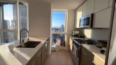 a kitchen with white counter tops and stainless steel appliances in front of a large window