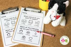 two worksheets on the floor next to a stuffed animal and a cup of crayons