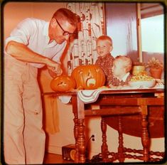 an old photo of a man carving pumpkins with two young children on the table