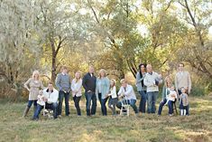 a group of people posing for a photo in front of some trees and grass with one person holding a baby