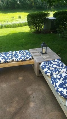 a bench made out of pallet wood with blue and white cushions on it in the middle of a yard