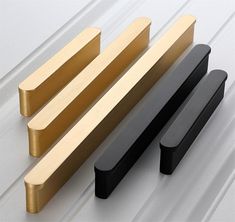 three different types of wooden handles on a white surface, one is black and the other is gold