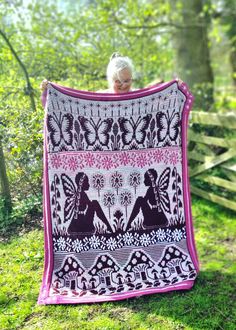 an older woman holding up a blanket in the woods