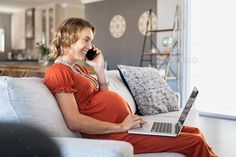 a pregnant woman sitting on a couch talking on her cell phone while using a laptop computer