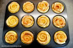 twelve cupcakes in a muffin tin with orange swirled icing on them