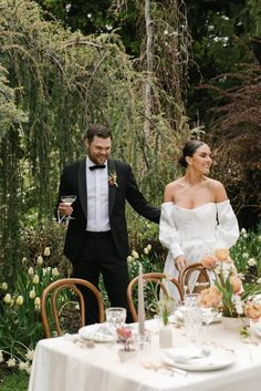 a man and woman standing next to each other near a table with flowers on it