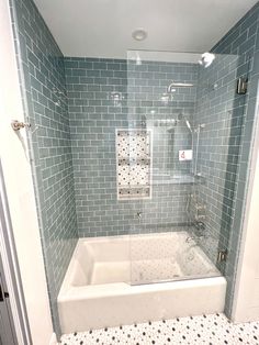 a bath tub sitting inside of a bathroom next to a walk in shower and tiled walls