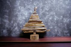 a small wooden christmas tree sitting on top of a table next to a gray wall