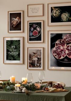 a dining room table with pictures on the wall above it and candles in front of them