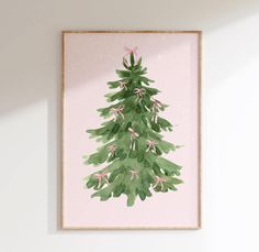 a green christmas tree with pink bows hanging on a wall in a white walled room