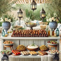 an outdoor buffet with lots of food on the table and hanging lights in the background