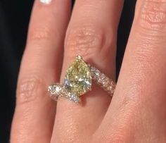 a woman's hand with a yellow and white diamond ring on it