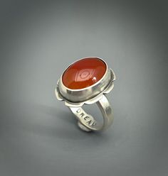 Carnelian gemstone ring set in sterling silver.  I added the word *Dream* to the inside of the ring. Women size 8 Sterling silver setting. Carnelian 12 carats 19m x13mm My signature and .925 are on the piece. All my pieces are 100% handmade by me. Please note that this ring cannot be resized because of the stone. My rings are all handmade and hand sawed. I do not cast rings. All my turquoise and other gemstones are sourced from highly reputable dealers. All my pieces are genuine. Some stones may have inclusions. That is the nature of the gemstone.  I try my outmost best to take pictures that reflect the true color of the stones. Some monitors may vary and affect the way you might see it but hopefully not. The fit is different on the wider bands. I try and accommodate for that size differen Anniversary Carnelian Rings With Polished Finish, Unique Carnelian Ring For Anniversary, Gemstone Rings Unique, Cast Rings, Red Gemstone Ring, Hand Saw, Red Gemstones, Ring Women, Jewelry For Her