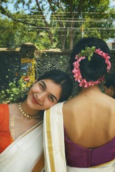 two women in sari are smiling for the camera while one woman is holding her head behind her back