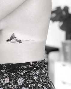 a black and white photo of a woman's stomach with a bird tattoo on it