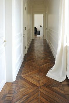 an empty hallway with wooden floors and white walls