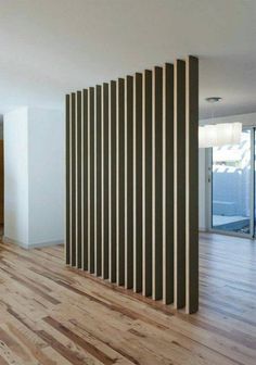 an empty room with wooden floors and vertical slats on the wall, in front of a sliding glass door