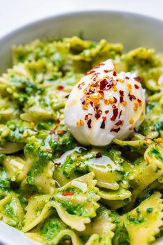 a white bowl filled with pasta and broccoli covered in cream sauce, garnished with sprinkles