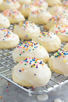 white frosted cookies with sprinkles on a cooling rack