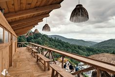 people are standing on the balcony of a wooden house with mountains in the back ground