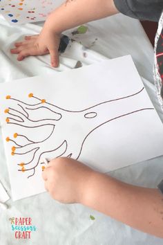 a young boy is drawing on paper with crayons