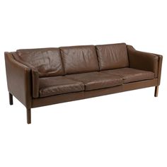 a brown leather couch sitting on top of a white floor