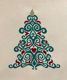 a cross stitch christmas tree with hearts on it's side, in green and red