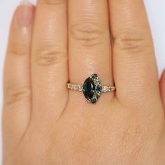 One Of A Kind Blue Green Marquise Sapphire Engagement Ring. Center stone is a 1.3 carat marquise shape Green Natural Sapphire (10 mm by 5 mm approximately). Flanked by .60 carat 5 blue green natural sapphires and .25 carat 7 Gray and Champagne Natural Diamonds. Set in 14k Rose Gold or 14k Yellow Gold or 14k White Gold. Please choose the color at checkout. The rings in the pictures are sold. Yours will be custom made once you make the purchase. You can choose rose gold or white gold or yellow gol Marquise Sapphire And Diamond Ring With Accent Stones, Blue Marquise Cut Diamond Ring, Marquise Sapphire Diamond Ring, Sapphire Gemstone Ring With Marquise Cut, Marquise Sapphire Ring With Halo Setting, Sapphire Marquise Center Stone Jewelry, Marquise Sapphire Promise Ring, Marquise Sapphire Ring As Gift, Sapphire Jewelry With Marquise Cut And Accent Stones