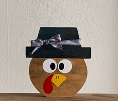 a wooden turkey with a black hat on it's head sitting on a table