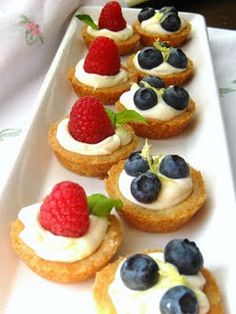 a white plate topped with mini desserts covered in whipped cream and fresh berries on top