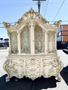 an old white china cabinet sitting in the middle of a parking lot