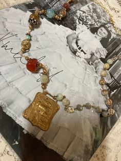 This is a handcrafted vintage assemblage necklace. Started with a vintage gold tone train watch fob. I added one side of rosary style, beads and earth tone colors. The opposite side is a variety of green rust and earth tone, beads, rondelles, and accent beads. It is very unique and one of a kind! No returns. Ship to continental  US only. Bohemian Medallion Necklace With Vintage Charm, Vintage Bronze Beaded Brass Necklaces, Bohemian Antique Gold Jewelry For Vintage Collection, Vintage Beaded Antique Gold Necklace, Antique Gold Beaded Vintage Necklace, Eclectic Gold Jewelry For Jewelry Making, Eclectic Gold Jewelry Gift, Unique Gold Necklaces From Vintage Collection, Unique Gold Necklaces With Vintage Charm