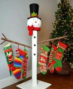 a snowman made out of socks and stockings hanging on a clothes line next to a christmas tree