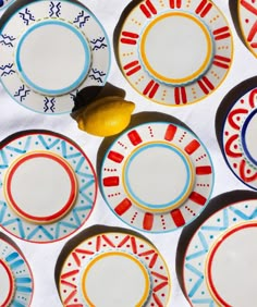 several plates with designs on them and a lemon sitting in the middle one is empty