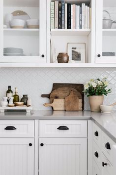 a kitchen with white cabinets and countertops has an old cutting board in the center