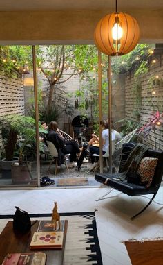 a living room filled with furniture and lots of plants on the floor next to a glass wall