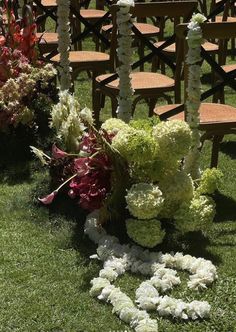 an arrangement of flowers on the ground in front of rows of wooden chairs